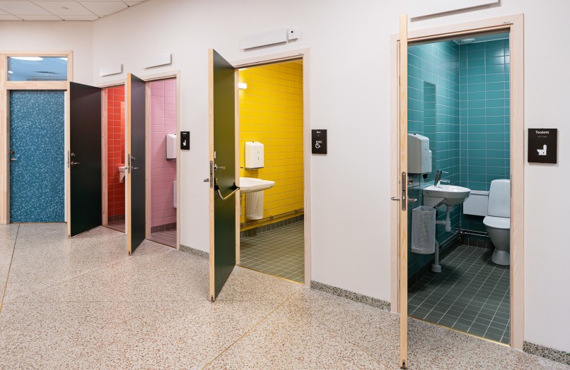 Toilets of different color on the tile.